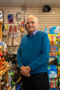 Prabhu Sharma, a shopkeeper in Grey Street, standing in his shop with sweets and sports equipment in the background.