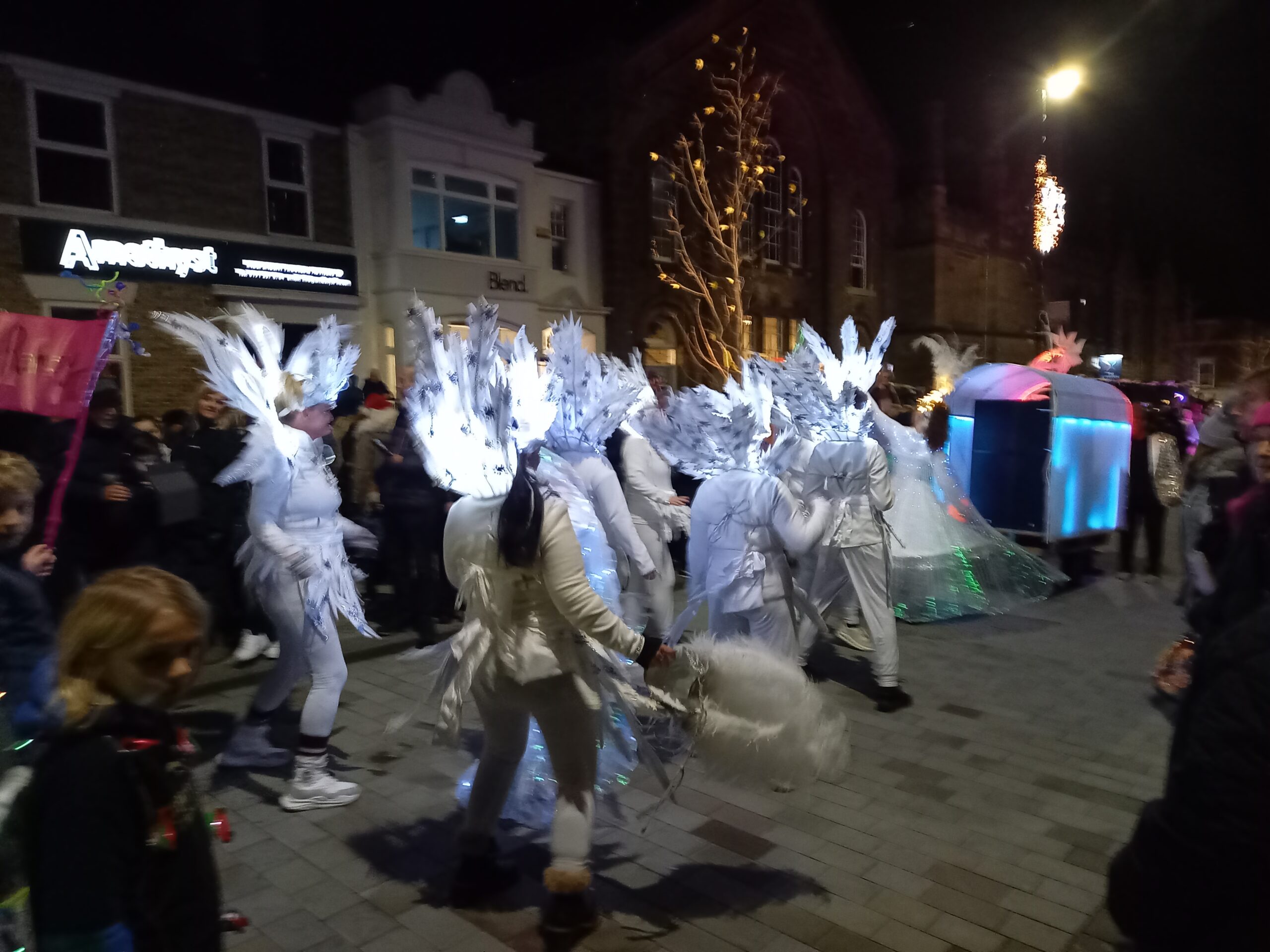 Illiminated dancers parading down Howard Street
